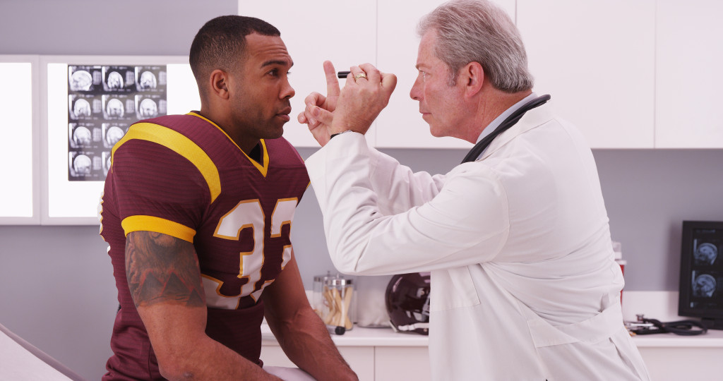 a male athlete getting checked out by doctor