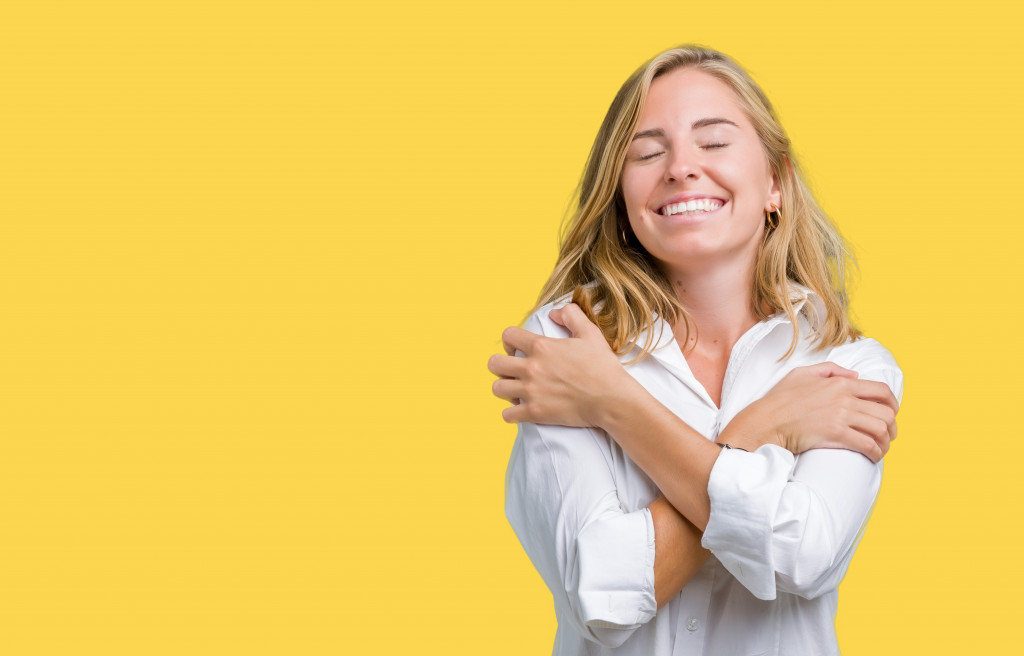 woman smiling and hugging herself